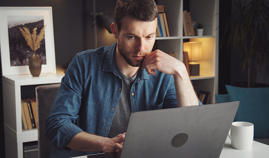 Young man working on a laptop from home, representing the digital client journey for researching legal services.